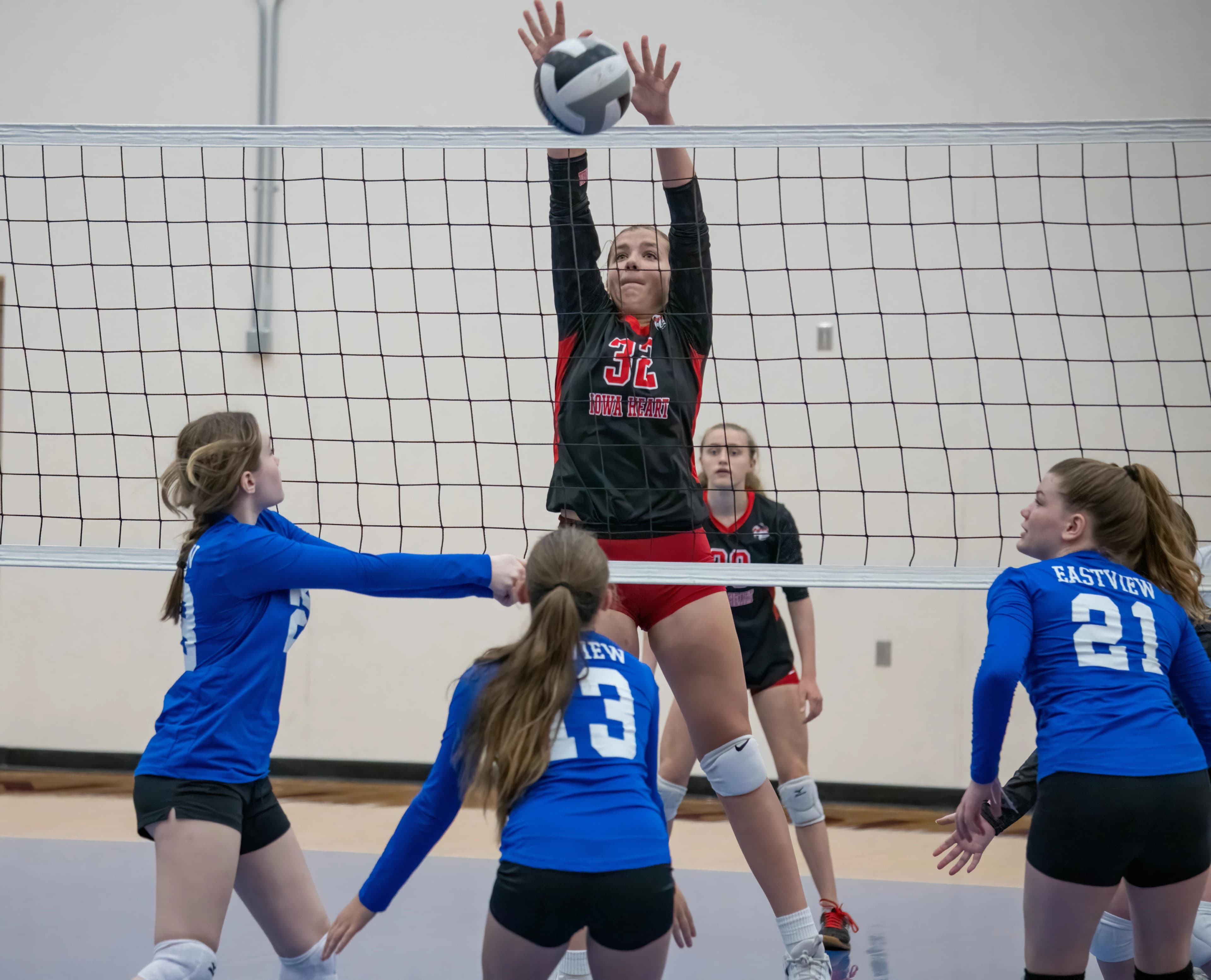 A volleyball player blocking at the net during a tournament match